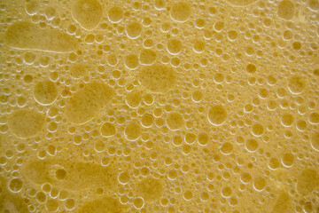 Air bubbles on the surface of the water. Fat rings in an aqueus emulsion. Yellow liquid with bubbles