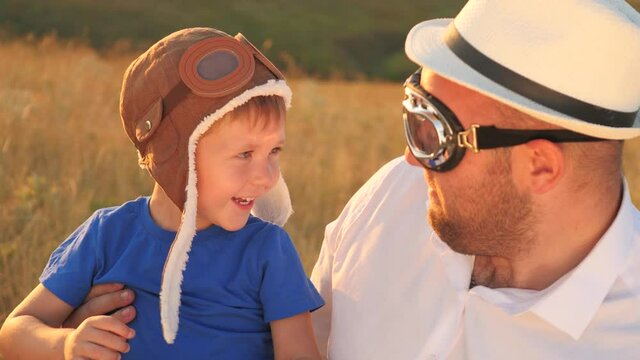 kid with dad dreams of flying, happy family, the life of a cheerful childhood, a boy and a father imagine playing an airplane, a little child in a helmet smiles at his parent, love baby, daddy's day