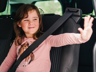 elementary child saying goodbye inside the transport vehicle with seat belt on