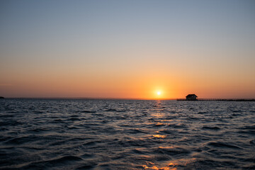 Sunset seen over bay with beach hut on pier 