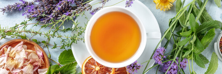 Tea panorama with herbs, flowers and fruit, shot from the top. Healthy organic hot drink