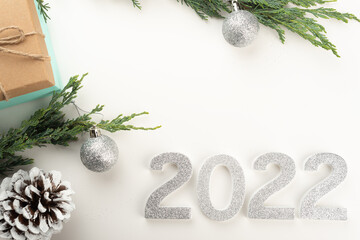 Flat lay with 2022 numbers, Christmas tree branches, pine cones, Christmas baubles, presents on light background.