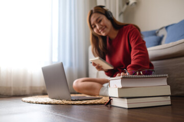 Fototapeta premium A young woman with headphone using laptop computer for online study at home