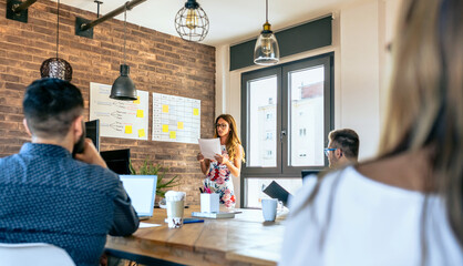 Female manager reading documents to workers in a work meeting