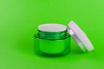 Green jar with a light day moisturizing hyaluronic cream gel for the face on a green background close-up