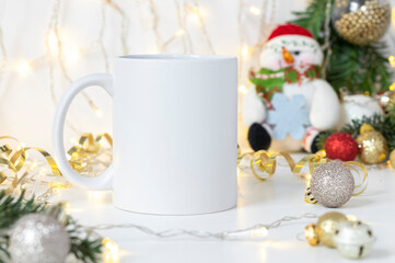 Obraz na płótnie Canvas White ceramic tea mug mockup with Snowman toy, winter x-mas decorations and copy space for your imprint. Front view 10oz cup background for Christmas promotional content