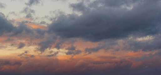 Naklejka na ściany i meble A fiery orange, pink and gentle blue sunset sky. Dramatic blue-gray clouds after rain. Panorama