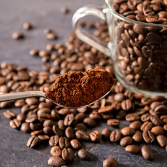 Coffee spoon with ground coffee. Coffee beans in a glass coffee cup in a background. Selective focus.