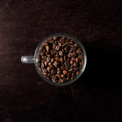 Coffee beans in a glass coffee cup against dark background.
