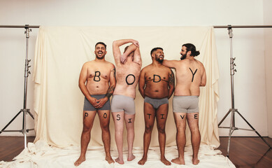 Body positive men standing shirtless in a studio