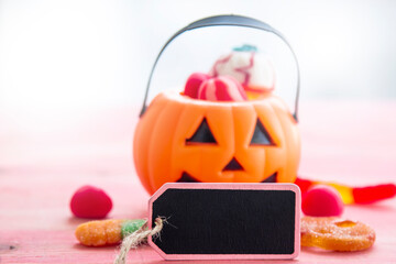 pumpkin with candies and label on pink background background. happy Halloween