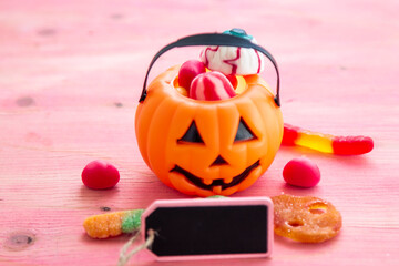 pumpkin with candies and label on pink background background. happy Halloween