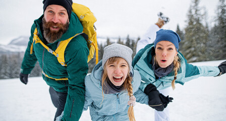 Family with small daughter having fun outdoors in winter nature, looking at camera.
