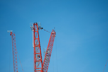 Red tower crane against blue sky background © Dontree