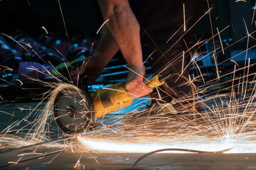 Worker working with a circular grinder on a metal with sparks flying out of them