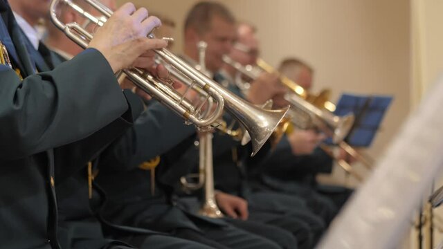 Brass military band.Hands close-up playing instruments.The orchestra is playing indoors.