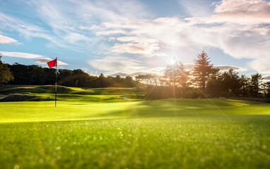 Golf course putting green with flag at sunset - Powered by Adobe