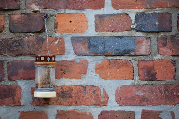 A candle hanging on an old brick wall. - obrazy, fototapety, plakaty