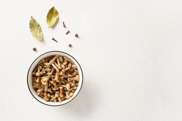 Pickled honey mushrooms in bowl on white background. Top view. Copy space.