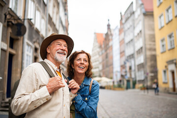 Portrait of happy senior couple tourists outdoors in historic town - obrazy, fototapety, plakaty