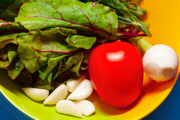 Vegetables on a plate for salad . Tomatoes garlic onion and beet leaves