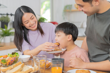Obraz na płótnie Canvas Happy refreshment family breakfast in morning, asian young parent father, mother and little cute boy, child having meal in kitchen eating together at home. Cheerful, enjoy cooking people.