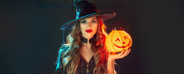 Halloween Witch holding Pumpkin lantern over black background. Decoration, hanging Jack-o-Lantern...