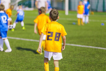 Kids in Soccer Jersey Uniforms Playing Junior League Game. Happy Boys Kicking Ball on Grass Venue. Two Children Football Teams in Yellow and Blue Shirts