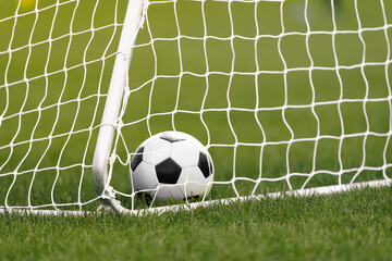 Football Ball in a Goal. Soccer Ball Lying in Grass. Football Equipement. White Soccer Goal and Net