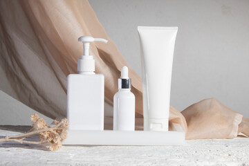 white wood table background with fabric textile, cosmetic makeup bottle lotion cream product with...