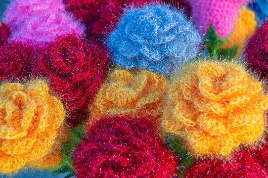 Handmade yarn flowers. A bouquet of flowers knitted from wool. Background of multicolored flowers. Wool products. Handmade decoration. © Eduard Belkin