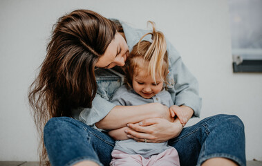 Portrait of happy young mother with her little daughter hugging on white background.