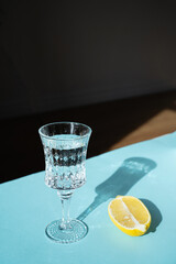 Top view of glass cap with lemon half on blue background. Sunny day with sharp shadows. Slimming diet for better metabolism
