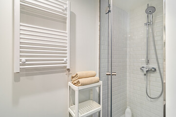 Interior of white bathroom with shower zone and towels heater