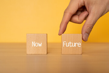 「Now」「Future」と書かれた積み木と人の手
