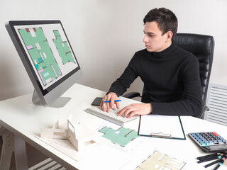 Fototapeta na wymiar Student to study to be architect. Concept - trained in architectural bureau. Young man works with construction drawings. Architect student is doing his thesis. Creation of construction drawings