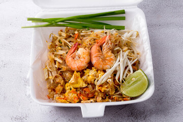 Fried noodle Thai style with prawns in foam box, Pad Thai with vegetables such as spring onions, lime, bean sprouts and tofu. popular street food of Thailand, Top view.