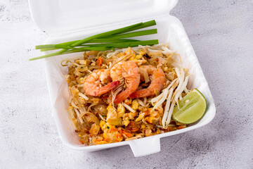 Fried noodle Thai style with prawns in foam box, Pad Thai with vegetables such as spring onions, lime, bean sprouts and tofu. popular street food of Thailand, Top view.