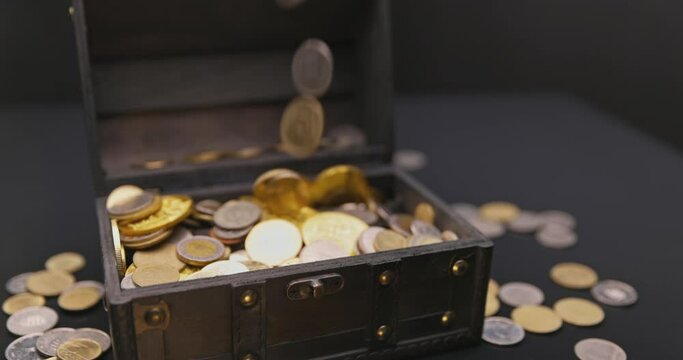 Money falling into treasure chest in slow motion