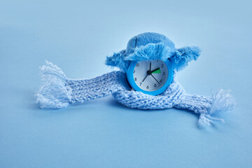 Clock changing from summer to winter time. Alarm clock with winter hat