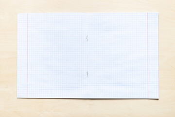 top view of blank open school notebook with squared sheets with margins on light brown wooden board