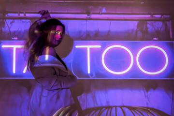 silhouette of a young beautiful woman on the background of neon projector inscriptions, slight blur