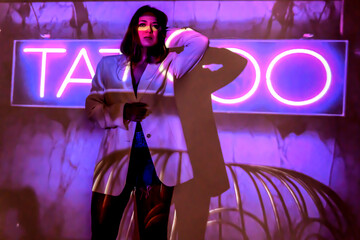 silhouette of a young beautiful woman on the background of neon projector inscriptions, slight blur