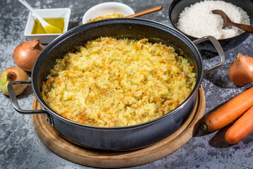 Italian vegan Risotto in a large pan with ingredients - rice, onion, carrots, spices, olive oil