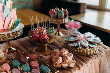 girl's birthday decoration on table delicious pink cupcakes and birthday cake