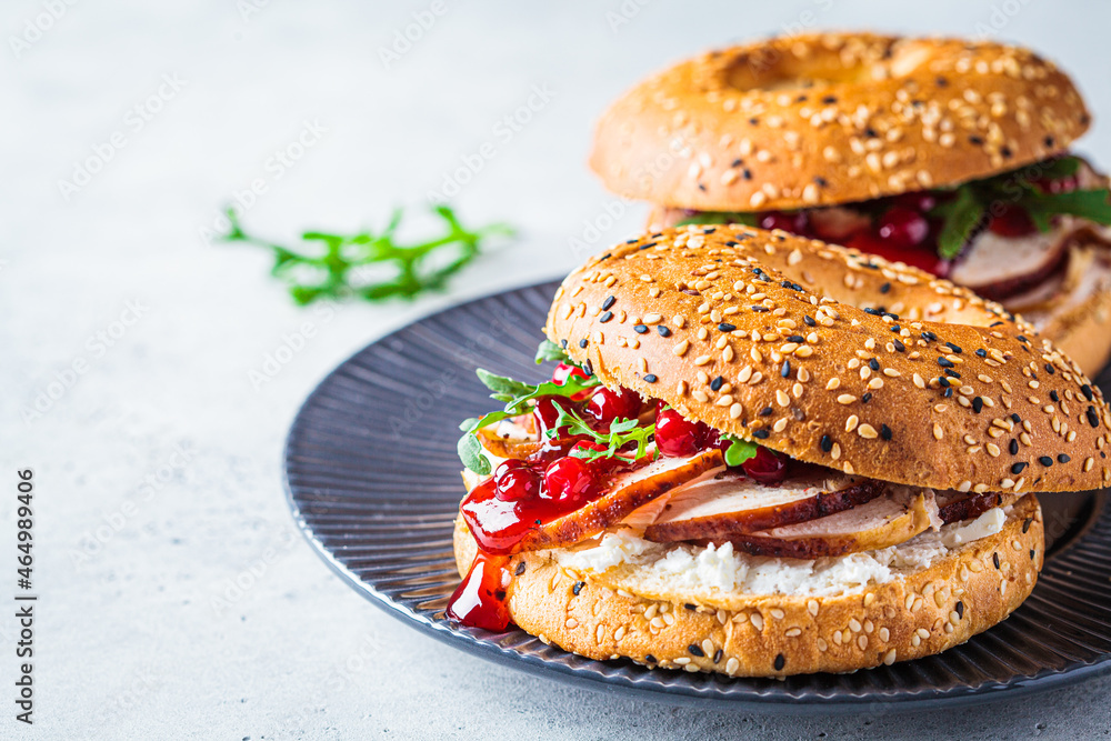 Wall mural Thanksgiving food concept. Bagel sandwich with turkey and cranberry sauce on a gray plate.