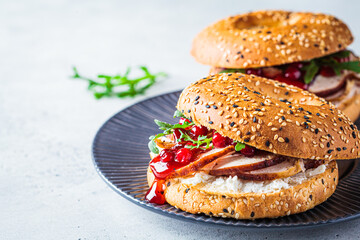 Thanksgiving food concept. Bagel sandwich with turkey and cranberry sauce on a gray plate.