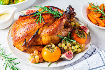 Roasted whole chicken served with fruits on plate, baked Brussels sprouts and carrots. Christmas or Thanksgiving food concept.