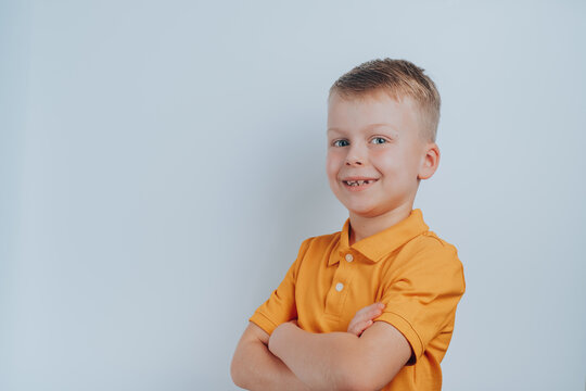 Portrait of a boy in a yellow T-shirt crossed his arms in front of his chest. on a gray background