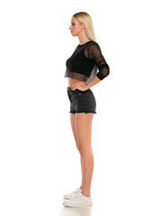 Side view of a young blond woman in short jeans and fish net blouse